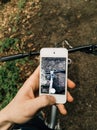 Man holding his smartphone capturing his bike bicycle on spring forest trail. Royalty Free Stock Photo