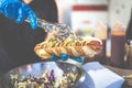 Man holding hot dog and adding vegetable salad. Street fast food vendor concept Royalty Free Stock Photo