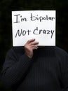 Man holding I`m bipolar not crazy homemade sign with dark background Royalty Free Stock Photo