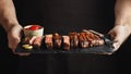 Man holding juicy grilled beef steak with spices and red sauce on a stone cutting board on a black background Royalty Free Stock Photo