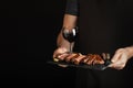 Man holding juicy grilled beef steak with spices and red wine glass on a stone cutting board on a black background. With Royalty Free Stock Photo