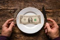 Man holding a knife and fork next to the plate which is one dollar