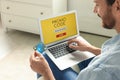 Man holding laptop with activated promo code and credit card indoors, closeup