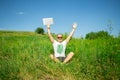 Man holding laptop in hand and put his hand up sitting in meadow Royalty Free Stock Photo