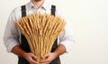 A man holding a large bundle of wheat on a white isolated background, symbolizing agriculture and harvest