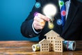 Man holding a light bulb over the house. Electricity, water, gas, heating, internet, security and surrounding infrastructure.