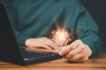 Man holding a light bulb while working on the computer to think and create new ideas with technological innovations and creativity Royalty Free Stock Photo