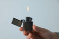 Man holding lighter with burning flame against light grey background, closeup Royalty Free Stock Photo