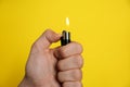Man holding lighter on yellow background, closeup Royalty Free Stock Photo