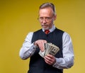Man holding lots of dollar bills in hands, isolated on yellow background. Happy man enjoying money Royalty Free Stock Photo