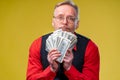 man holding lots of dollar bills in hands, isolated on yellow background. Happy man enjoying money Royalty Free Stock Photo