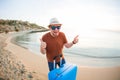 Man holding luggage and showing thumbs up against the blue ocean. Travel concept. Royalty Free Stock Photo