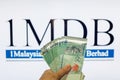 Man holding Malaysia Ringgit with burr 1MDB background indicating the US Government inves Royalty Free Stock Photo