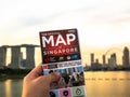 Man holding map of Singapore and background is Singapore skyline at evening in Singapore city Royalty Free Stock Photo