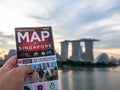 Man holding map of Singapore and background is Singapore skyline at evening in Singapore city Royalty Free Stock Photo