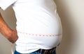 A man holding measurement tape around his waistline big fat belly, overweight man Royalty Free Stock Photo