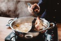 Man holding medium rare slice Wagyu A5 beef out from hot pot shabu shoyu soup base by chopsticks with steam