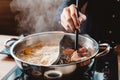 Man holding medium rare slice Wagyu A5 beef out from hot pot shabu shoyu soup base by chopsticks with steam