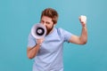 Man holding megaphone near mouth, loudly speaking, screaming, making announcement with raised arm. Royalty Free Stock Photo