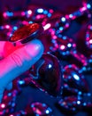 Man holding metal anal plug in neon pink purple light.