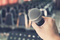 Man Holding Microphone over the Blurred Chairs in the Conference Royalty Free Stock Photo