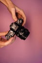 A man holding a mirrorless camera in his hands on a light background top view. photographer adjusts the camera close-up.