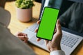 man holding mobile phone in hand with blank green screen. mockup