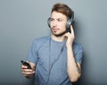 Man holding mobile phone and lictening to music over grey background Royalty Free Stock Photo