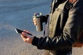 Man holding mobile phone and thermo cup, travel mug.