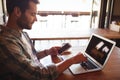 Man holding mobile phone while using laptop Royalty Free Stock Photo