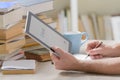 Man holding a modern ebook reader and book in library Royalty Free Stock Photo