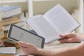 Man holding a modern ebook reader and book in library Royalty Free Stock Photo