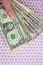 Man is holding money in hand on the background with pink hearts. Loving dollars. Time to go shopping and buy things. Money