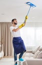 Man cleaning ceiling and lamps in living room. House cleaning service concept.