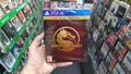 Man holding Mortal Kombat 11 Premium edition videogame on Sony Playstation 4 console in store