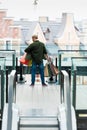 Man holding multicolord paper bags while standing on escalator in shopping mall Royalty Free Stock Photo