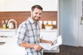 Man holding newspaper while leaning on kitchen counter Royalty Free Stock Photo