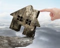 Man holding old house on cliff edge with hand pushing Royalty Free Stock Photo