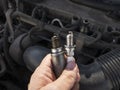 Man Holding old and new car spark plugs on engine background Royalty Free Stock Photo