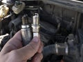 Man Holding old and new car spark plugs on engine background Royalty Free Stock Photo