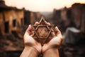A man holding an old and rusty star of David in their hands on ruins background. Royalty Free Stock Photo