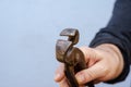 A man is holding old tongs in his hand. A rusty metal hand tool