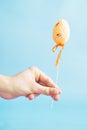 Man holding an orange Easter egg on a stick on a blue background Royalty Free Stock Photo