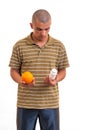 Man holding an orange in one hand and pills in another