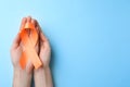 Man holding orange ribbon on light blue background, top view with space for text. Multiple sclerosis awareness