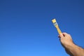 Man holding paint brash against of the blue sky Royalty Free Stock Photo