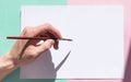A person holds a brush with his left hand and prepares to draw on paper. Royalty Free Stock Photo