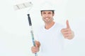 Man holding paint roller while gesturing thumbs up