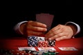 Man holding a pair of playing cards while playing poker with chips and cards in front of him Royalty Free Stock Photo