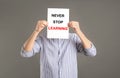 Man holding paper with phrase NEVER STOP LEARNING on background